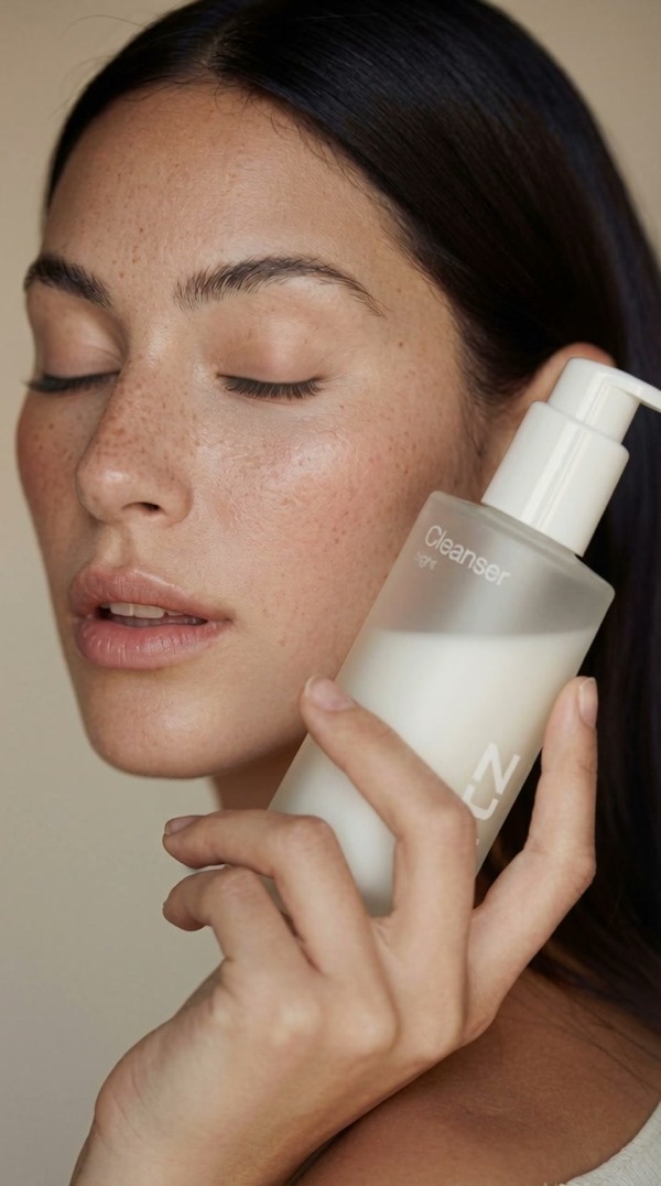 Skincare serum held to the light, soft daylight portrait