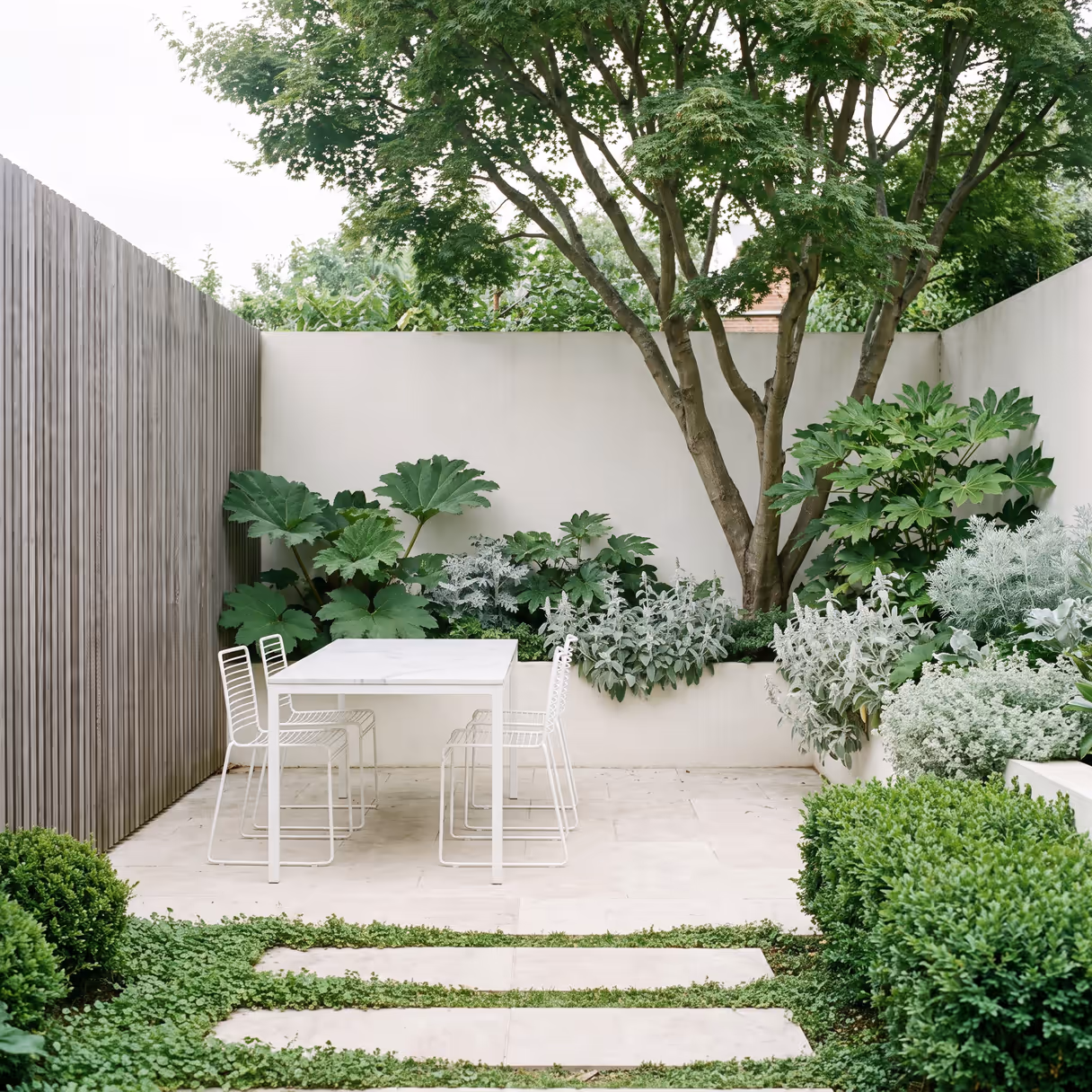 A table set under a mature tree in a finished garden