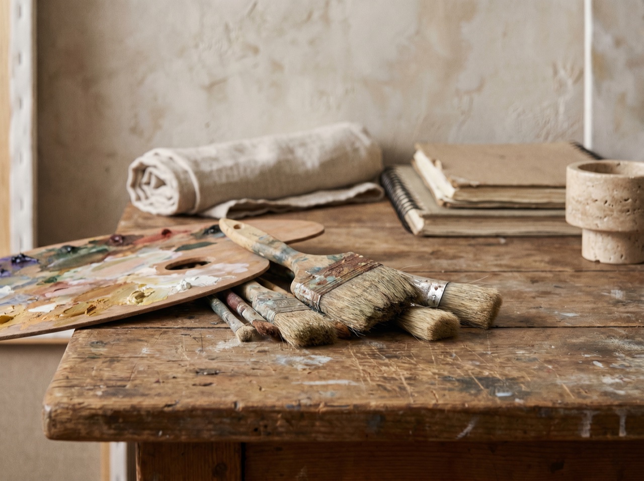 An artist's brushes and palette resting on a worn studio table