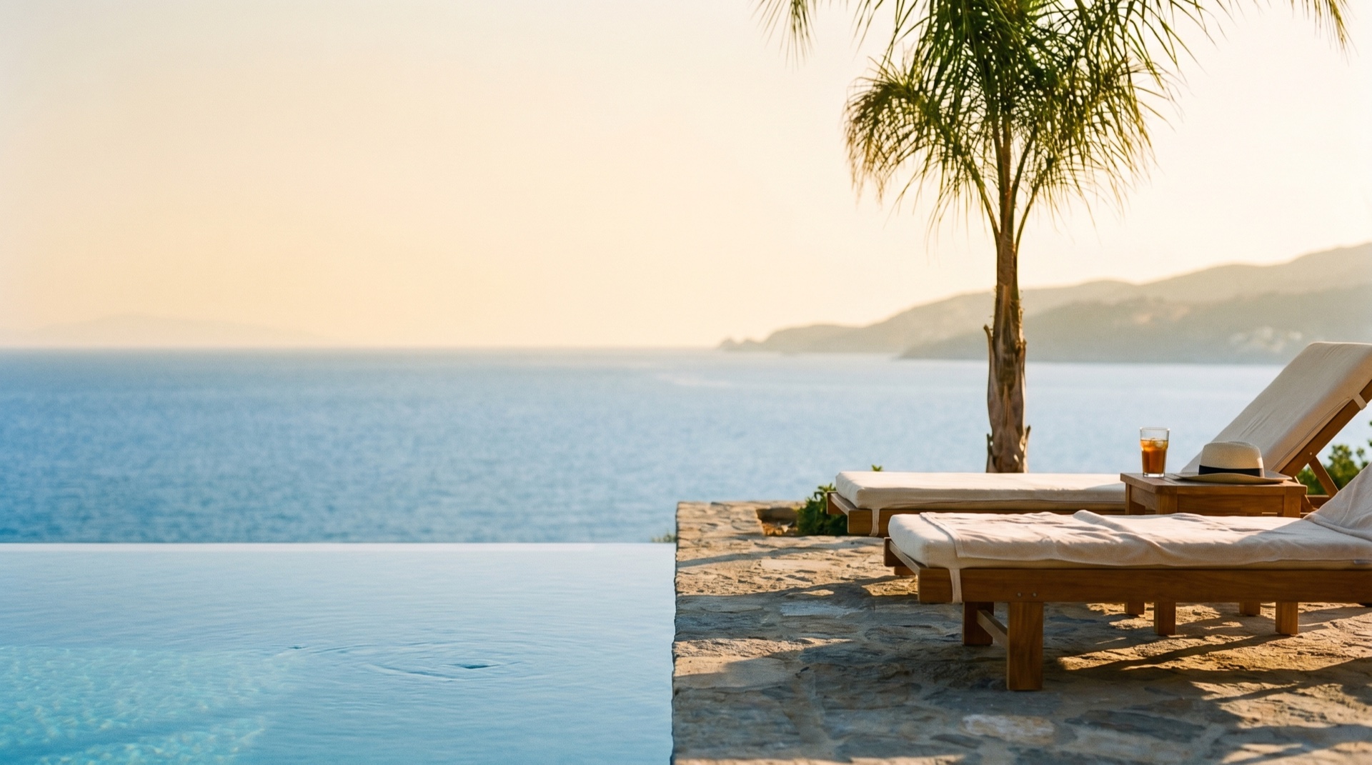 A serene resort infinity pool meeting the sea at golden hour, soft warm light, generous negative space