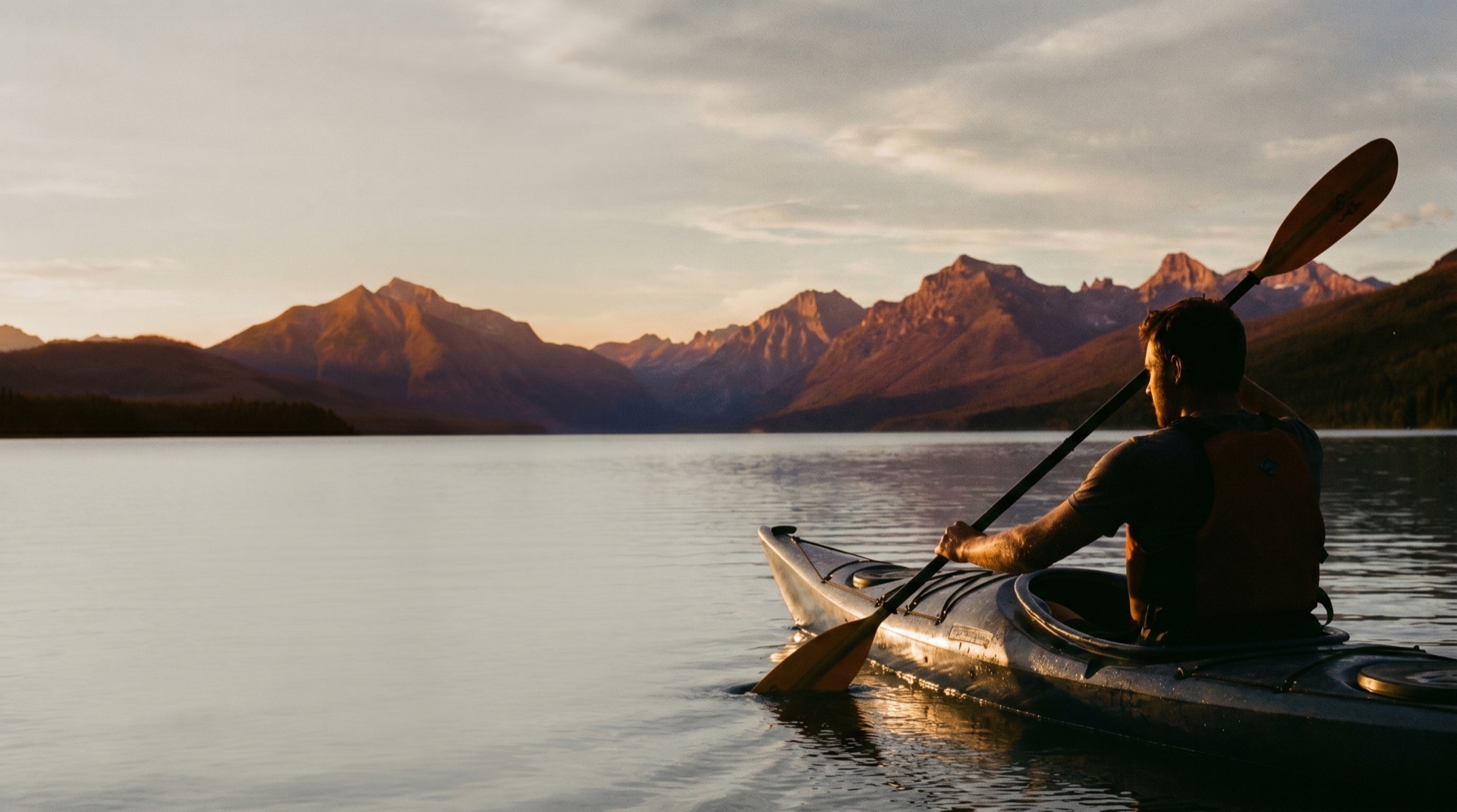 A wide outdoor adventure scene at golden hour, a kayak on still water under open sky, generous negative space